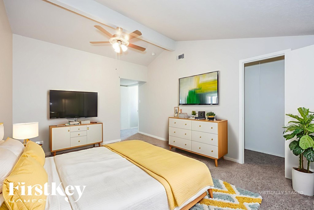 A bedroom with a bed, dresser, and ceiling fan.