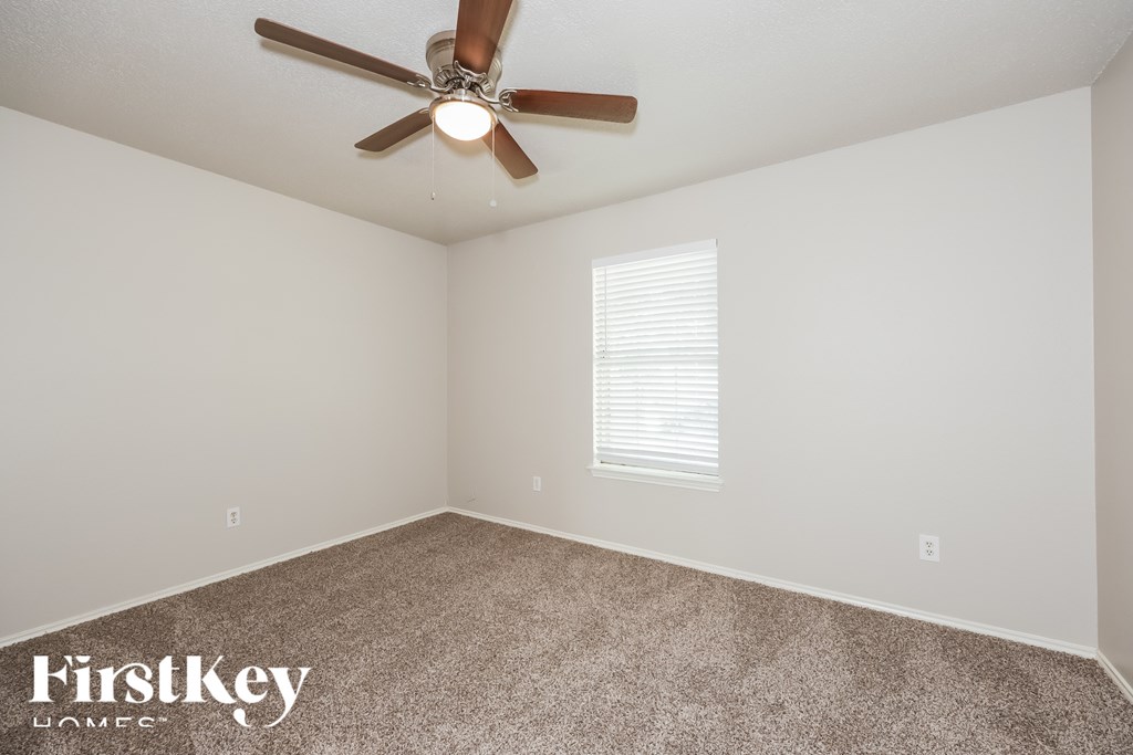 A room with a ceiling fan and a window with blinds.