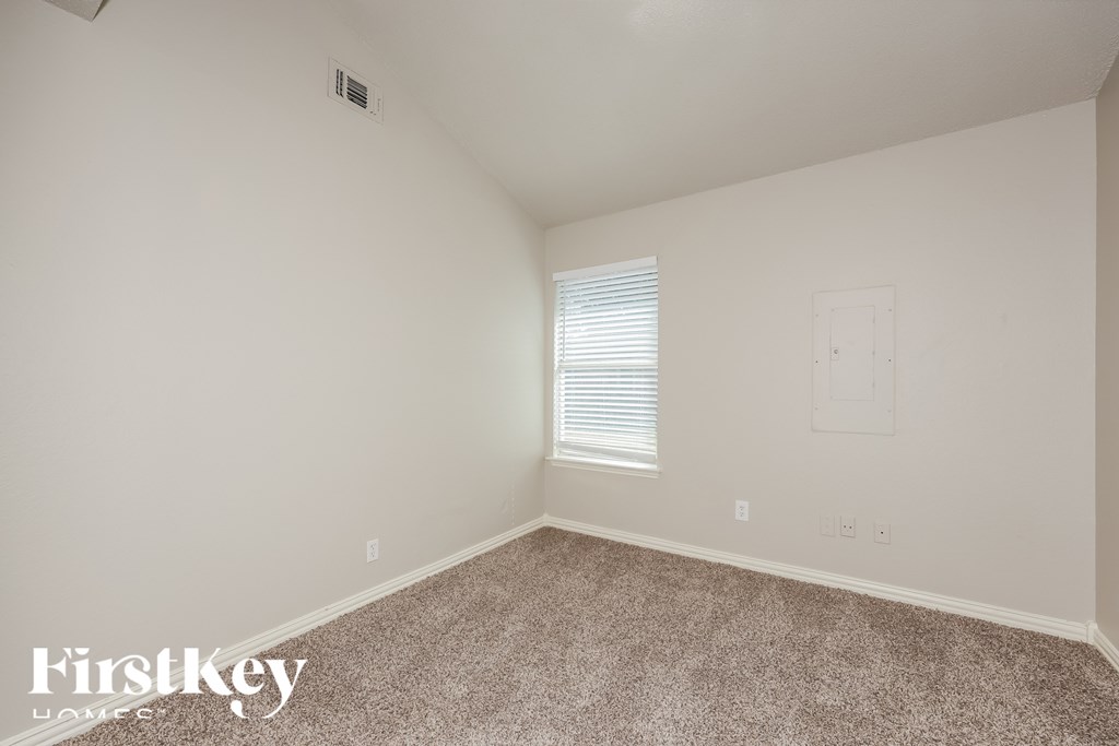 A room with a carpeted floor and a window with blinds.