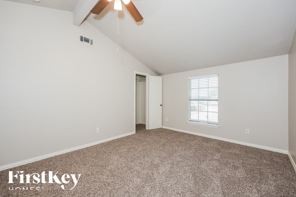 A room with a carpet floor and a ceiling fan.