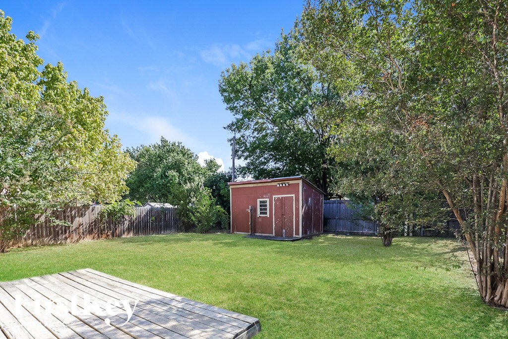 A red shed sits in a grassy backyard.
