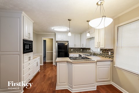 A kitchen with white cabinets and a black fridge.