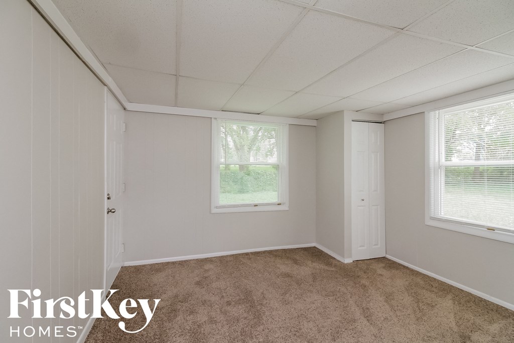 a bedroom with a carpeted floor and two windows