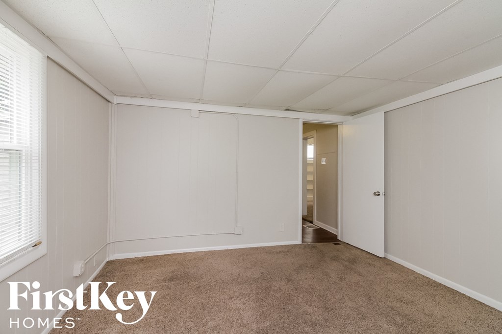 a bedroom with white walls and carpet and a door to a closet