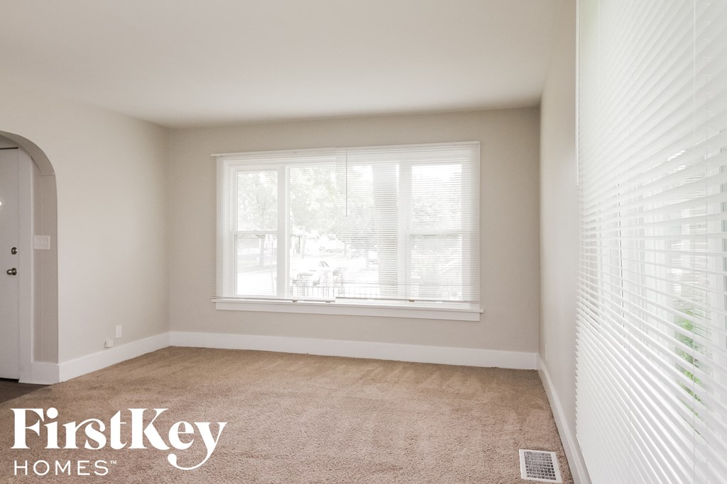 a bedroom with a large window and a carpeted floor