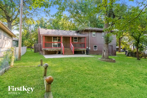 a small red house with a porch and a grassy yard