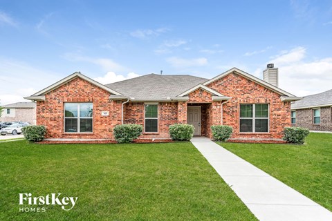 a brick house with green grass and a sidewalk