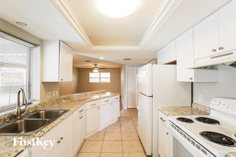 A kitchen with white cabinets and a stove top oven.