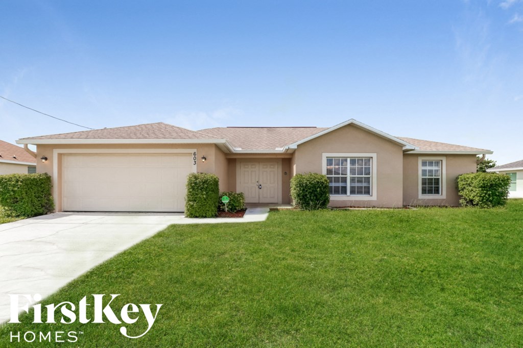 A house with a garage and a driveway in front of it.