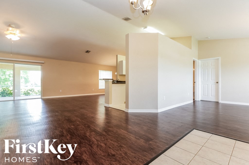 A spacious room with wooden floors and a chandelier.