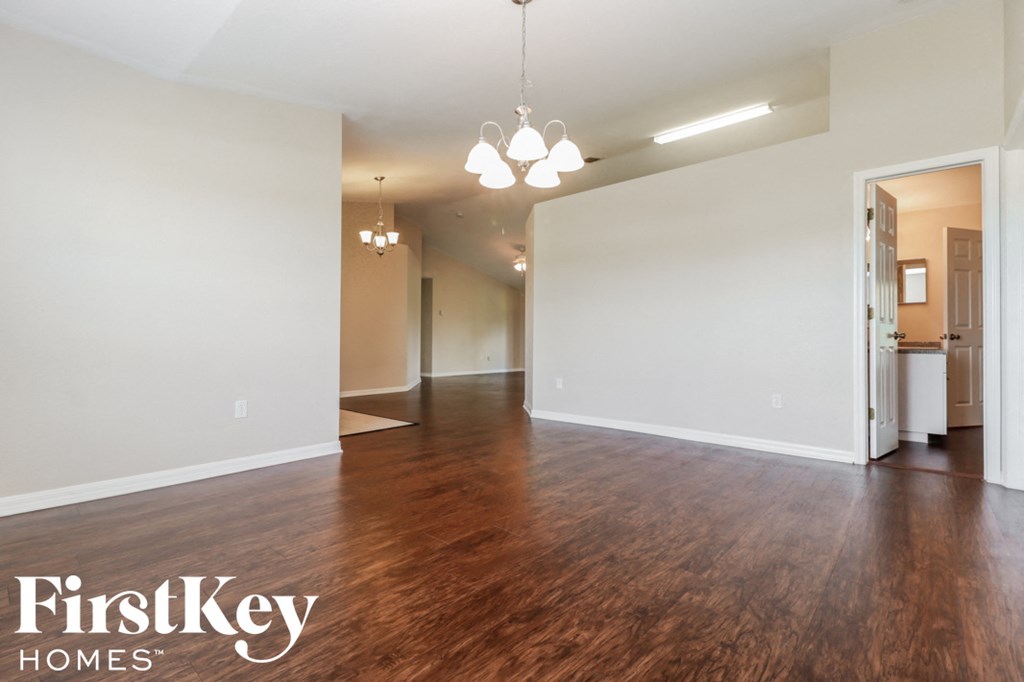 A large empty room with wooden floors and a chandelier.