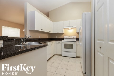 A kitchen with a black counter top and white appliances.