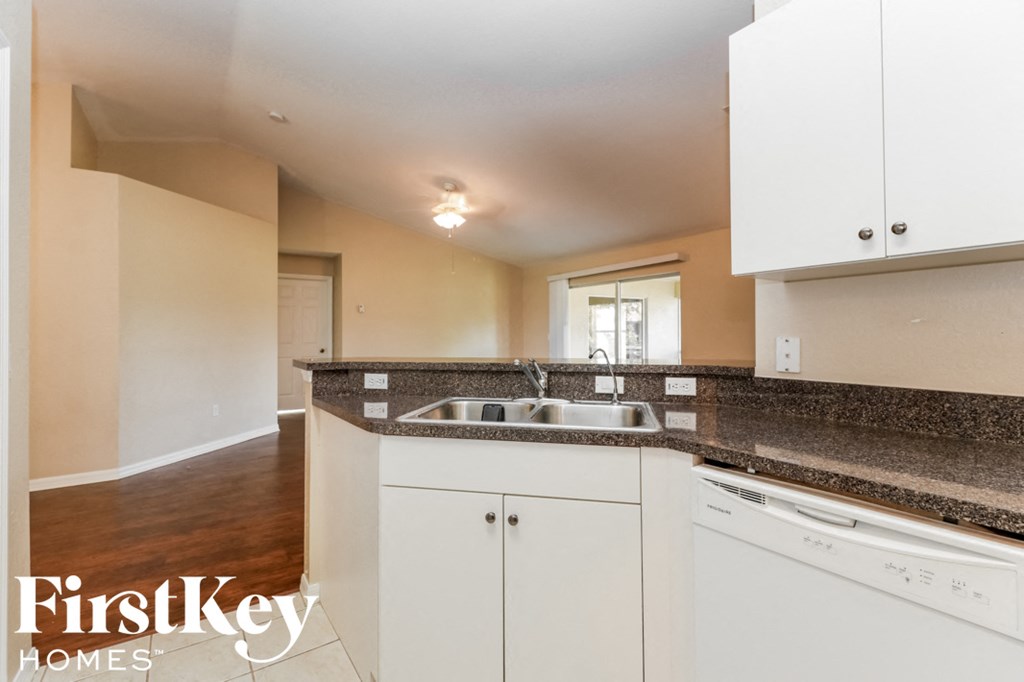 A kitchen with white cabinets and a granite countertop.