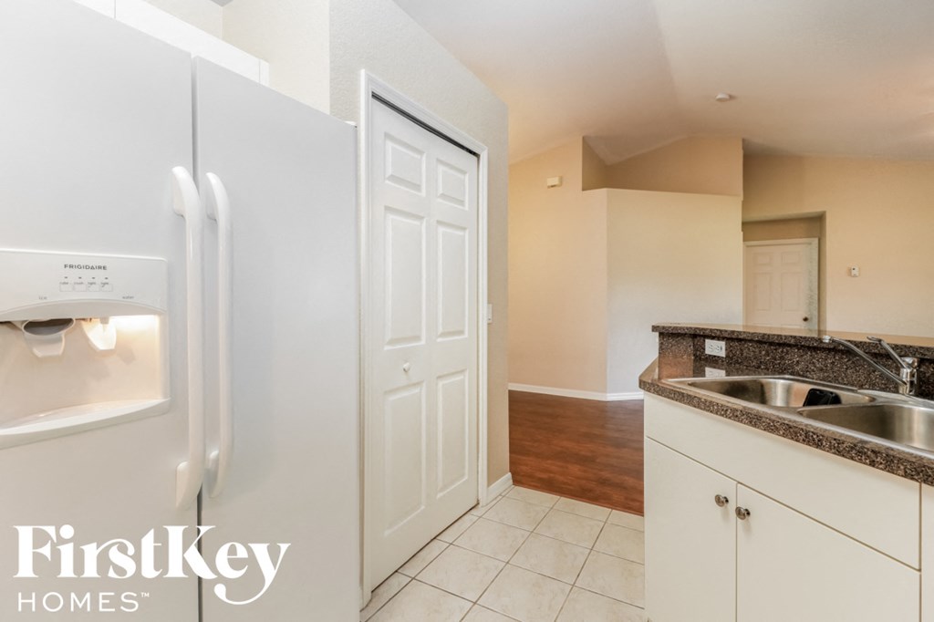 A kitchen with a white fridge and a white door.