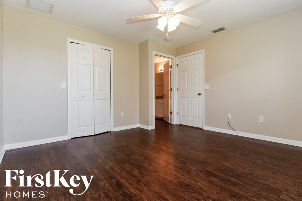 A room with a ceiling fan and wooden floors.