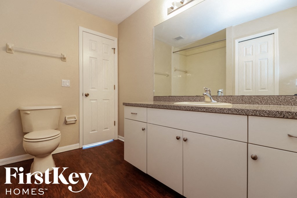 A bathroom with a toilet, sink, and mirror.
