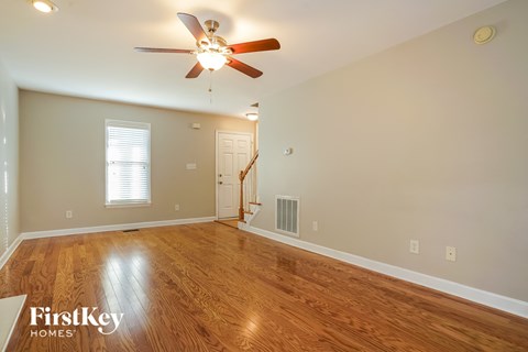 A spacious room with a wood floor and a ceiling fan.