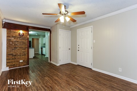 A room with a ceiling fan and wooden floors.