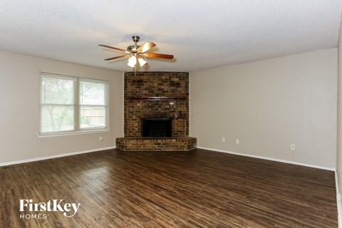 A spacious room with a fireplace and a ceiling fan.