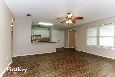 A spacious room with a ceiling fan and wooden flooring.