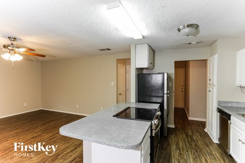 A kitchen with a black stove top oven and a fan on the ceiling.