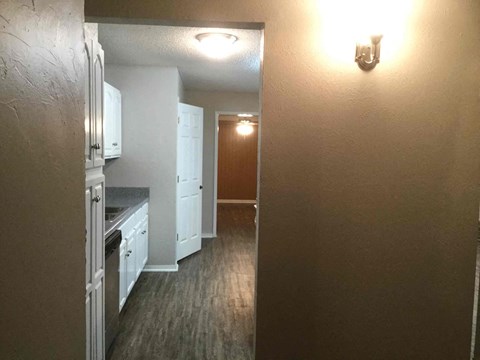 A kitchen with white cabinets and a wooden floor.