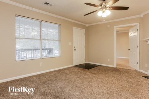 A room with a carpeted floor, a ceiling fan, and a window with blinds.