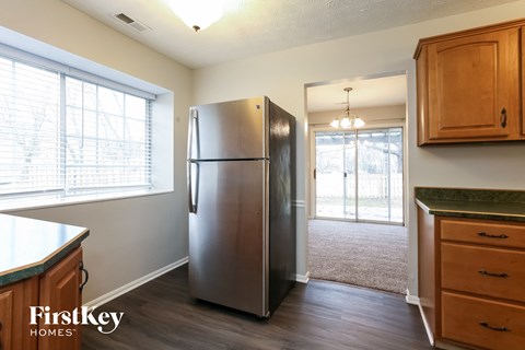 A kitchen with a stainless steel refrigerator and wooden cabinets.