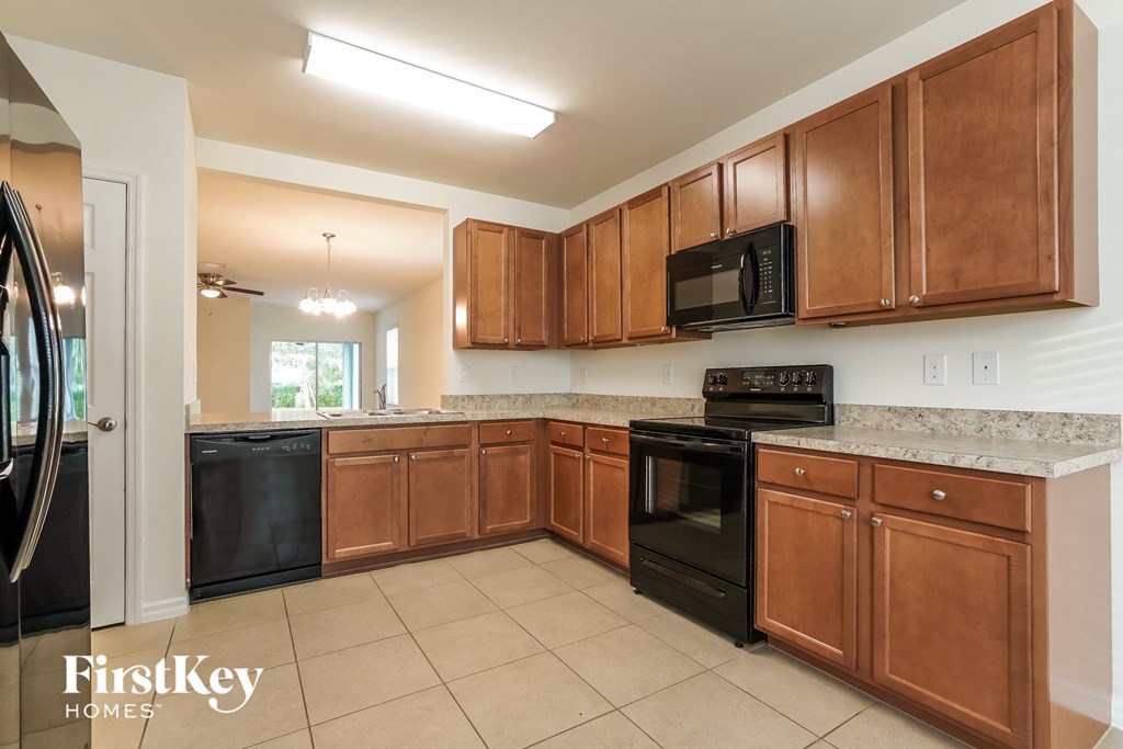 A kitchen with brown cabinets and black appliances.