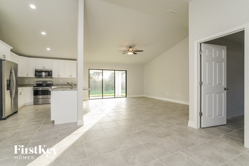 A spacious kitchen and living room with a sliding glass door leading to a backyard.