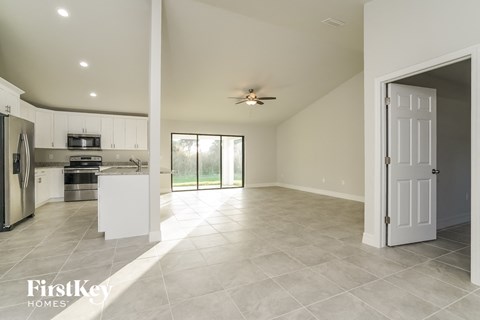 A spacious kitchen and living room with a sliding glass door leading to a backyard.