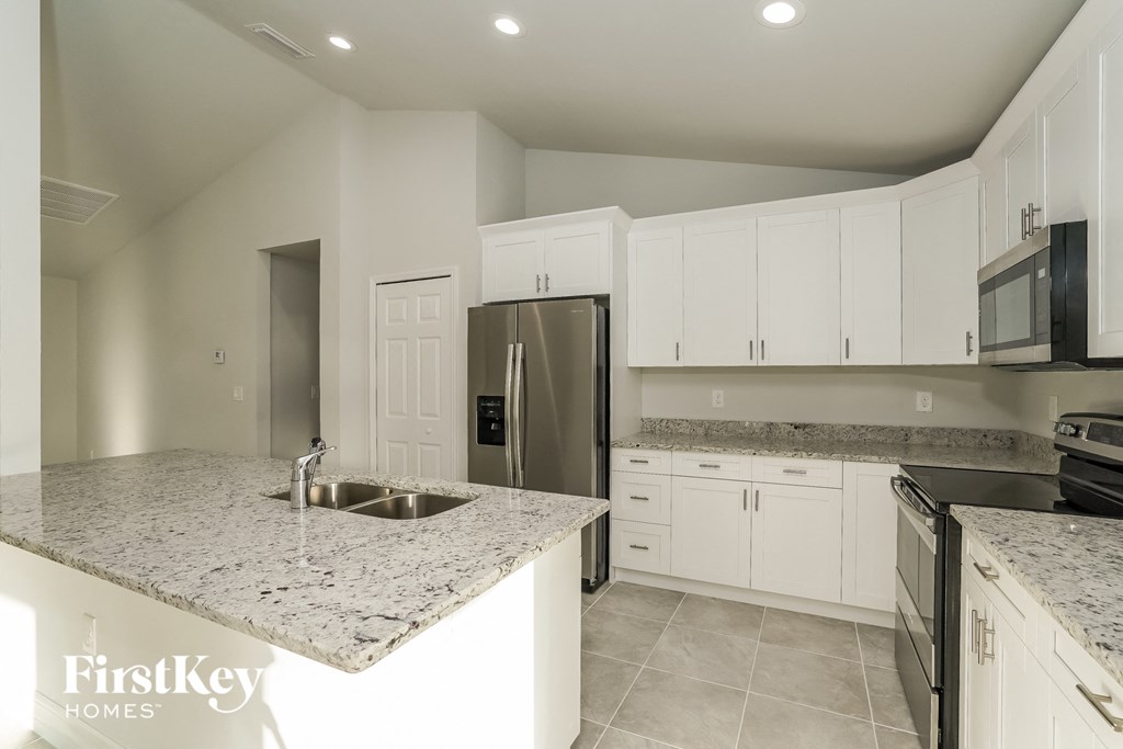 A kitchen with granite countertops and white cabinets.