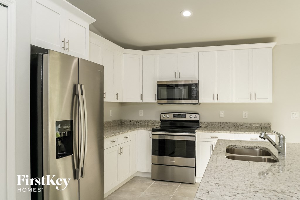 A kitchen with a stainless steel refrigerator, microwave, oven, and sink.