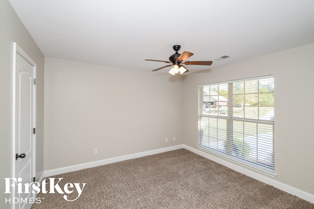a bedroom with a ceiling fan and a large window