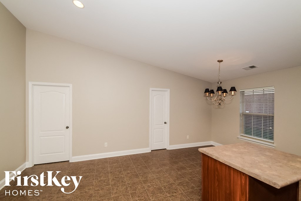 an empty dining room with a kitchen island and a chandelier