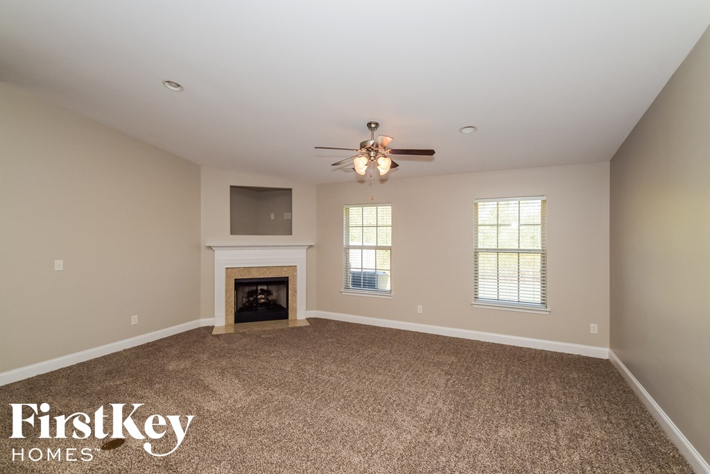 an empty living room with a fireplace and a ceiling fan