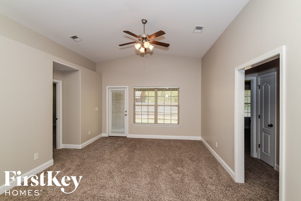 an empty living room with a ceiling fan and a window