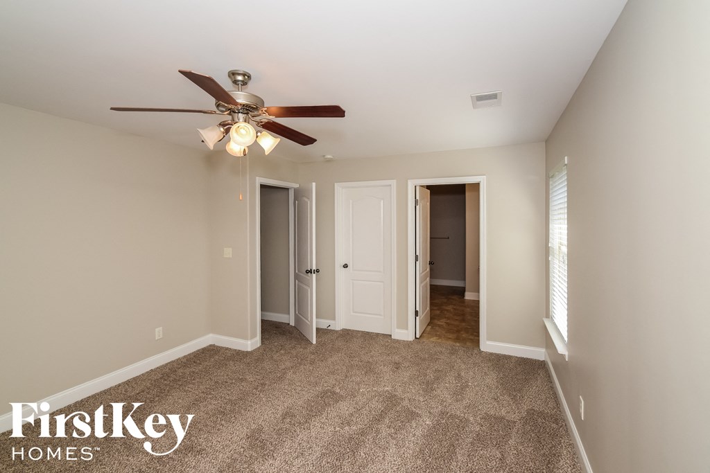 a bedroom with a ceiling fan and a door to a hallway