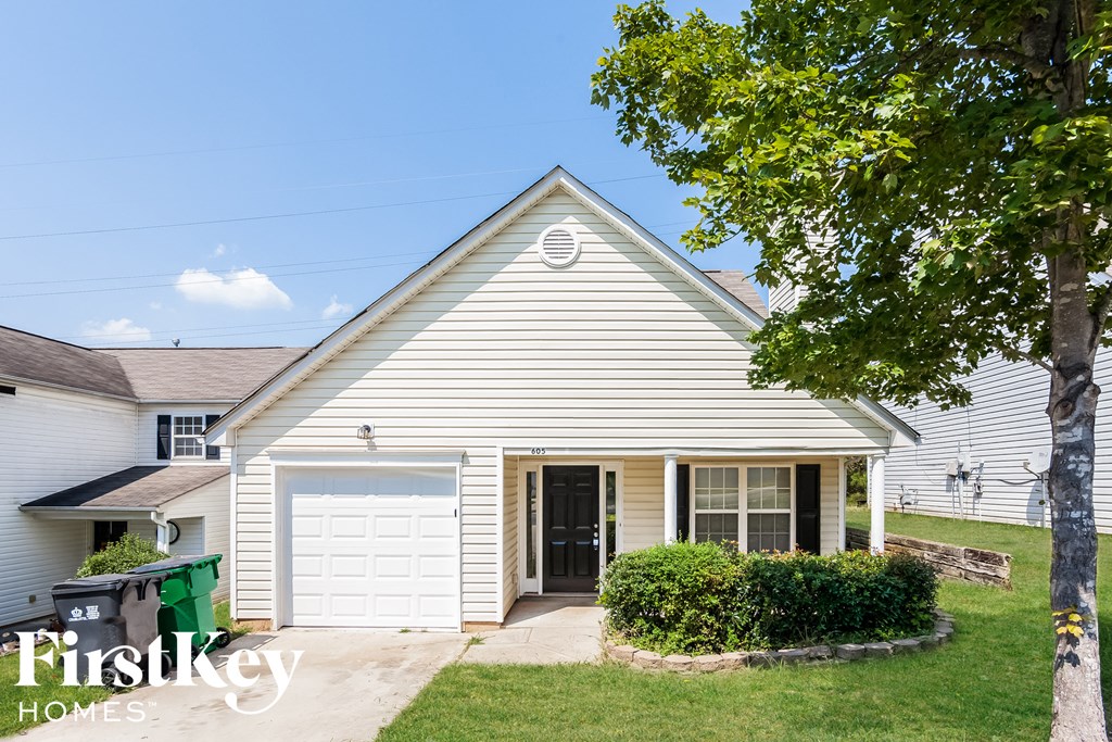 A house with a white garage door and a tree in front.