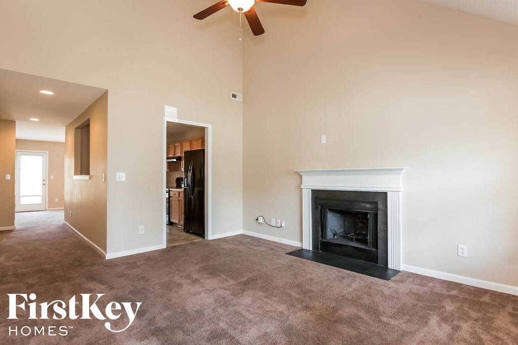 A living room with a fireplace and a ceiling fan.