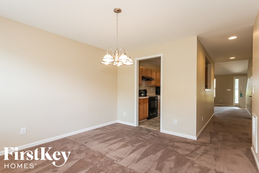 A spacious room with a carpeted floor and a chandelier hanging from the ceiling.