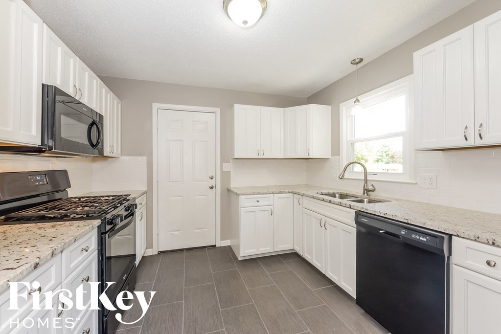 A kitchen with white cabinets and a black dishwasher.