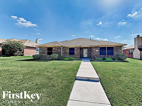 the front of a house with green grass and a sidewalk
