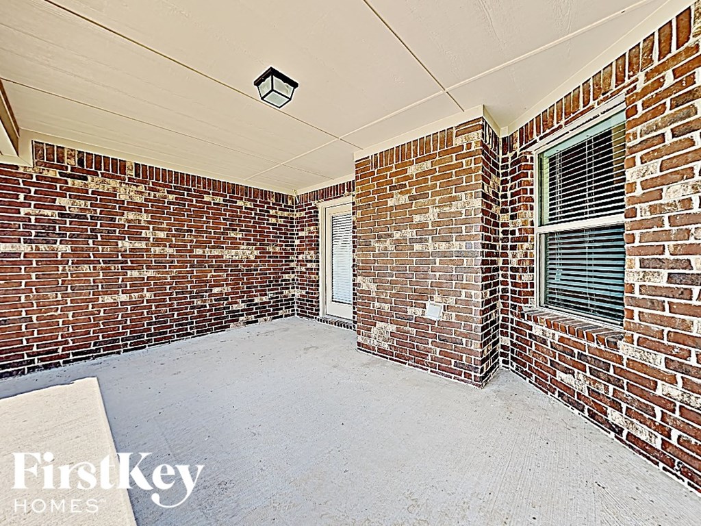 the patio of a brick house has a brick wall and a window
