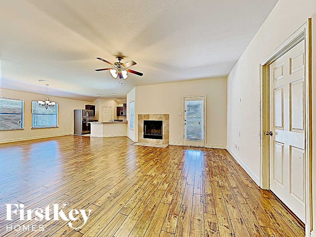 an empty living room with a fireplace and a ceiling fan