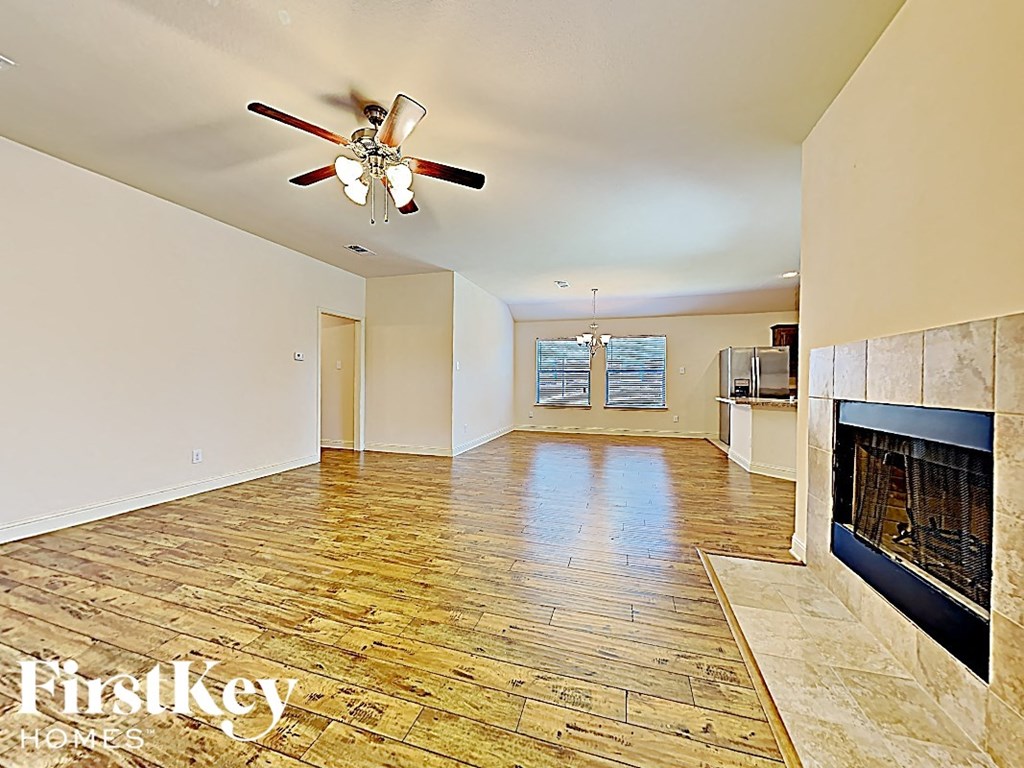 an empty living room with a fireplace and a ceiling fan