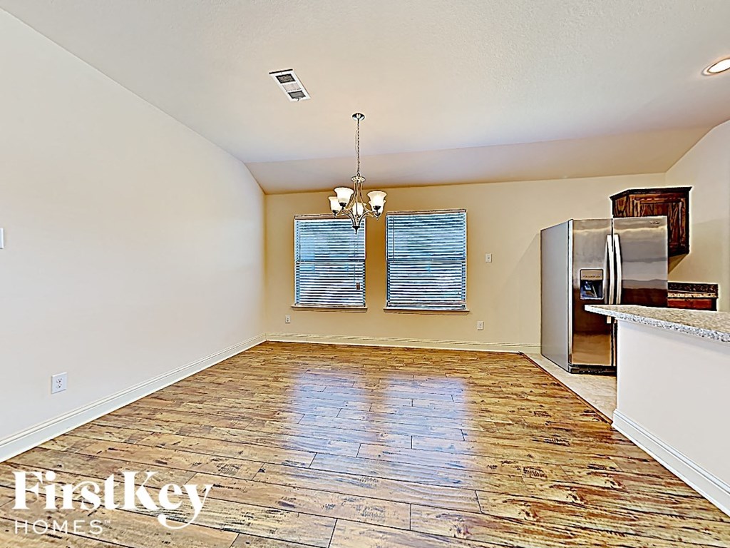 an empty kitchen with a stainless steel refrigerator and wood flooring