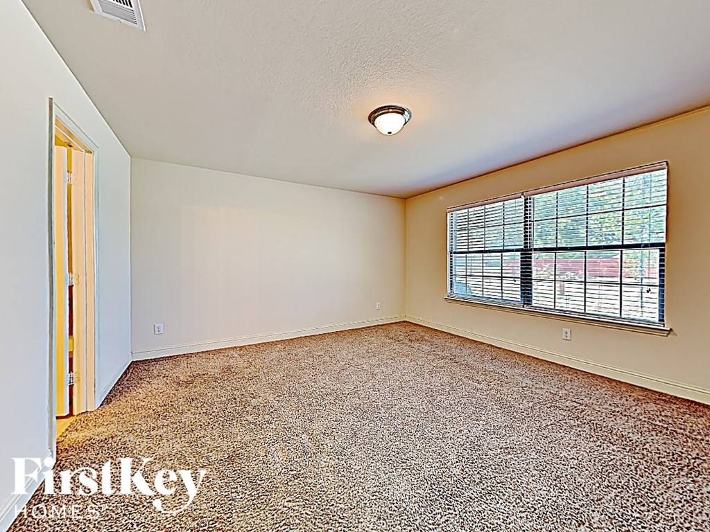 an empty living room with a large window and carpet