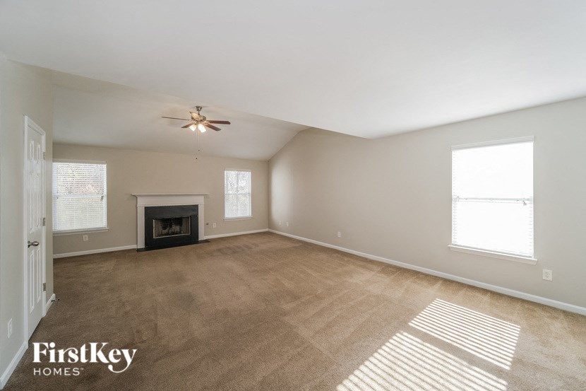 an empty living room with a fireplace and a ceiling fan
