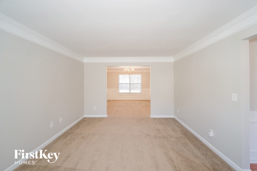 a spacious living room with white walls and a carpeted floor